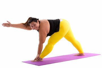 Studio shot of young happy fat Asian woman smiling while bending