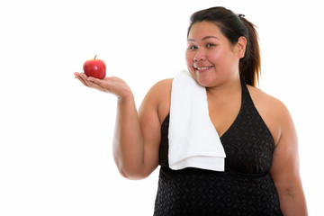 Studio shot of young happy fat Asian woman smiling and holding r