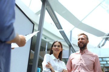 Group of young modern people in smart casual wear standing in creative office.