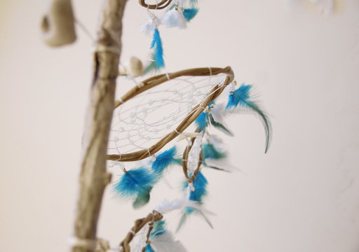 Photo of handmade dreamcatcher with feathers and beads on a white background, ethnic theme