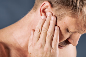 Fototapeta premium Man has a sore ear. Man suffering from headache on blue background