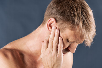 Fototapeta premium Man has a sore ear. Man suffering from headache on blue background