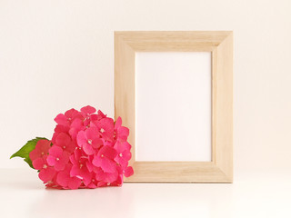 Hydrangea flower and blank photo frame on table in front of the wall.