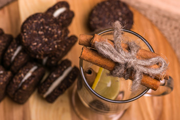 Cookies closeup. Chocolate cookies with nuts, cinnamon and cardamom on a wooden table. A glass with cinnamon and lemon.