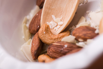 White crockery close-up with wooden spoon. Dishes with nuts and coconut.