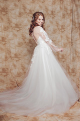 Fototapeta premium Beautiful and romantic bride in wedding dress with long sleeves. Young redheaded woman in wedding dress
