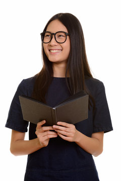 Young happy Asian teenage girl smiling while holding book and th