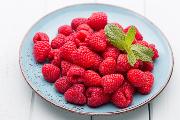 Fresh raspberries in a plate on a  vintage background.