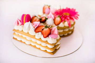 Tasty beautiful pink cake with strawberries, marshmallows, macaroons and huge flower gor the 2 years birthday party
