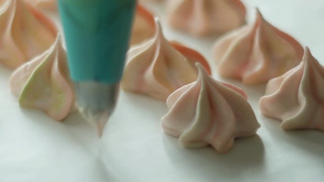 Hands of a chef cooking meringue. Pastry tube spread meringue on a baking sheet in the kitchen