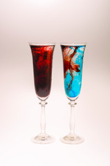 The effect of water smoke using an red and blue food coloring in two glasses for champagne on a white background.