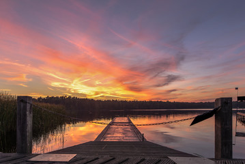 A day is coming to an end with a beautiful sunset on the lake with a boat dock. Concept: vacation and travel