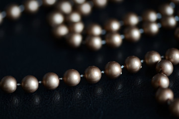 Long necklace of brown beads on a dark background close up