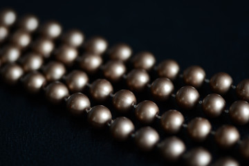 Long necklace of brown beads on a dark background close up