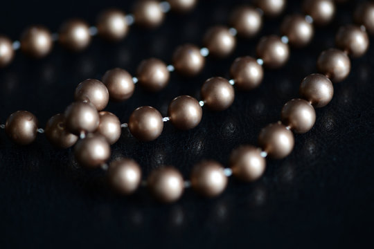 Long necklace of brown beads on a dark background close up