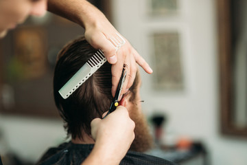 Barber using scissors and comb in barbershop