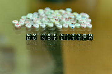 DO NOT LITTER  written with Acrylic Black cube with white Alphabet Beads on the Glass Background