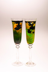 The effect of water smoke using an orange and green food coloring and ink in two glasses for champagne on a white background.