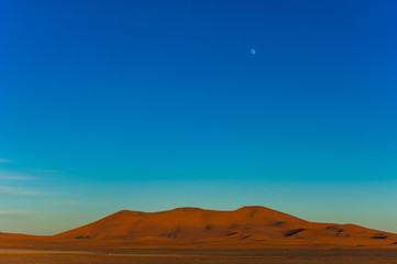 Fototapeta na wymiar Full moon over the sand dunes of the Sahara, Merzouga, Morocco, Africa