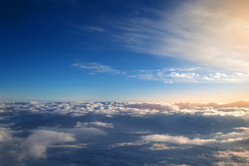 background of blue sky over cumulus clouds with the rays of the setting sun