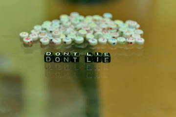 DONT LIE  written with Acrylic Black cube with white Alphabet Beads on the Glass Background