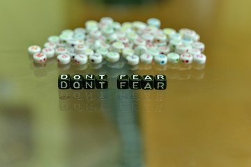 DONT FEAR  written with Acrylic Black cube with white Alphabet Beads on the Glass Background