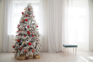 Christmas snowy Christmas tree with presents in a white room in winter