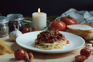 Spaghetti with red sauce on disk placing together with many recipes and candle on the wooden table