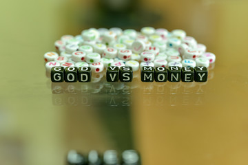 GOD VS MONEY  written with Acrylic Black cube with white Alphabet Beads on the Glass Background