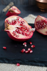pieces of pomegranate on slate tray. Dark and moody light concept. 