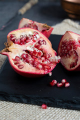 pieces of pomegranate on slate tray. Dark and moody light concept. 