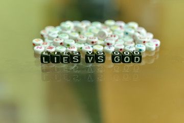 LIES VS GOD  written with Acrylic Black cube with white Alphabet Beads on the Glass Background