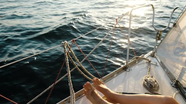 Female legs feet on the sailing yacht closeup in the open sea