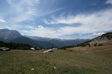 Fototapeta na wymiar Alpine mountain houses, meadows and cloudy sky