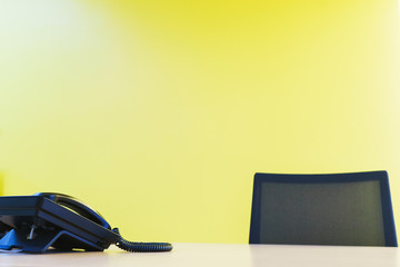 Clean office worker desk with black telephone and black armchair. 