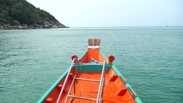 Traditional Thail long-tail boat, floats and move  forward in the middle of the sea. Wooden motor boat floating in the clear water