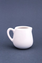 Ceramic white jug for milk on grey background. Mock up for design.