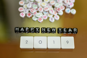 HAPPY NEW YEAR 2019 written with Acrylic Black cube with white Alphabet Beads on the Glass Background