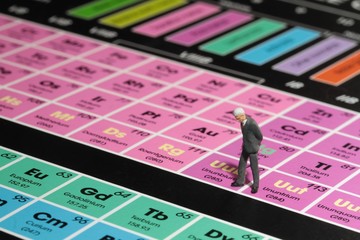 businessman in miniatura guarda la tavola periodica degli elementi chimici