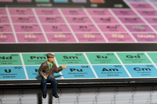 miniatura di persona seduta su tavola periodica degli elementi chimici