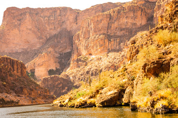 Arizona desert is diverse red slick rock cliffs surround Canyon Lake in the wilderness east of Phoenix with desert plants adding to the beauty of these landscape photographs