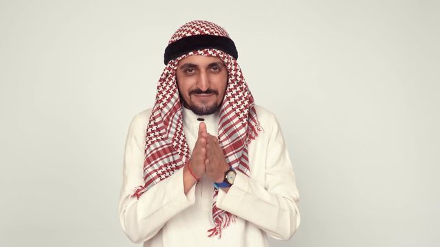 Modern Arab in the office. A man in national dress smiles and rejoices. The Arab rubs his hands and squints slyly.