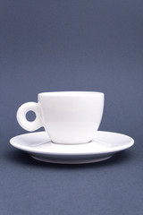 Ceramic white cup on saucer on grey background. Mock up for design.