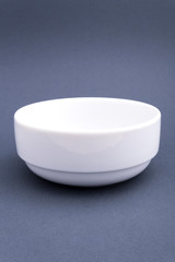 Ceramic white plate with a high side on grey background. Mock up for design.