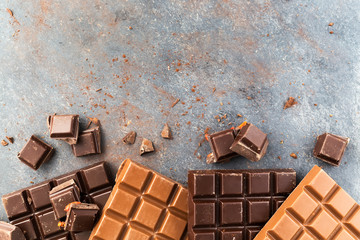 Milk and dark chocolate bars on a grey table. Top view