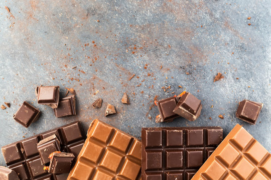 Milk and dark chocolate bars on a grey table. Top view