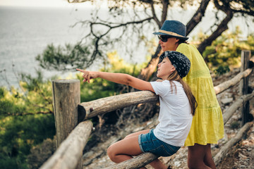 Mother and daughter standing next to wooden fence by the sea