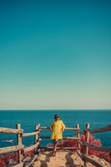Woman standing next to wooden fence by the sea