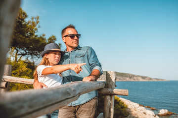 Father and daughter standing by the sea and looking into horizon