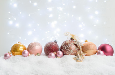 White christmas with snow - pink and golden balls with festive lights in background